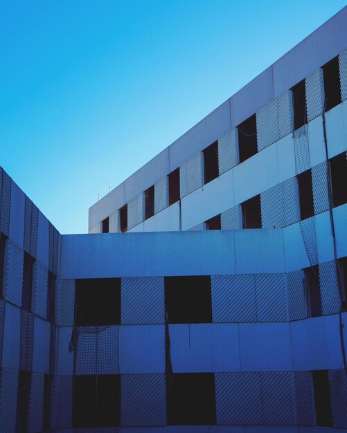 Low angle view of office building against blue sky