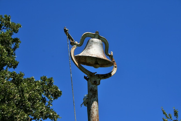 Foto vista a bassa angolazione della vecchia campana della chiesa contro un cielo blu limpido