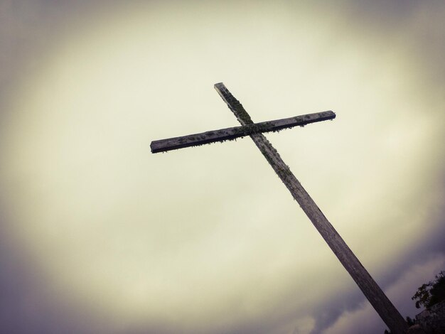 Low angle view of old cross against cloudy sky