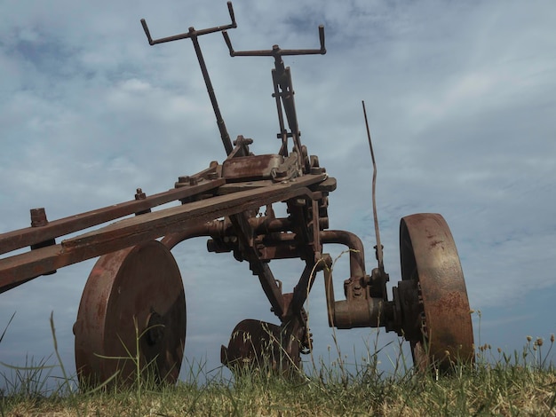 Photo low angle view of old machinery on field against sky