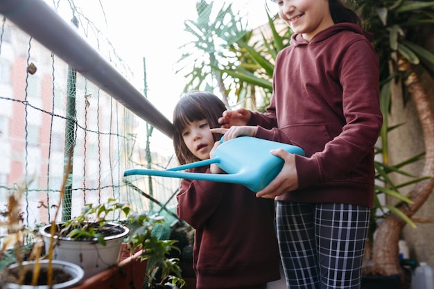 写真 一緒に植物に水をまくアパートのバルコニーで 2 人の子供の低角度のビュー