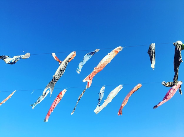 low angle view of paper fish hanging against blue sky
