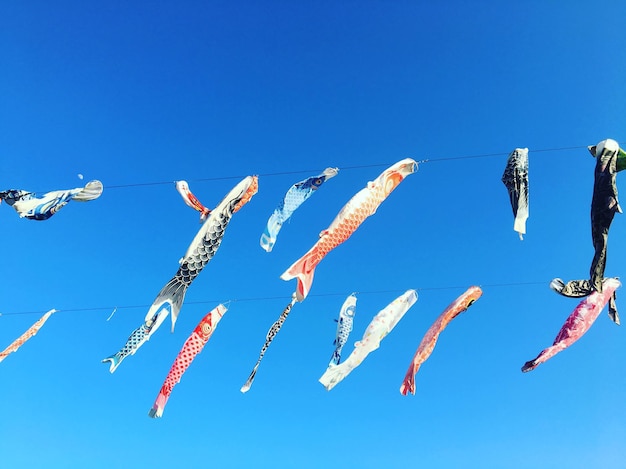 Low angle view of paper fish hanging against blue sky