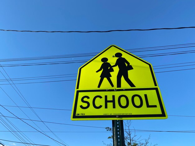 Photo low angle view of pedestrian crossing road sign against blue sky in mount vernon new york