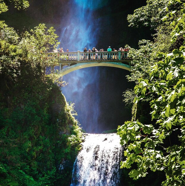 Low angle view of people on bridge against waterfall