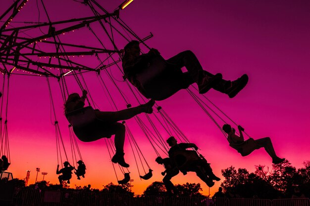 Photo low angle view of people enjoying chain swing ride