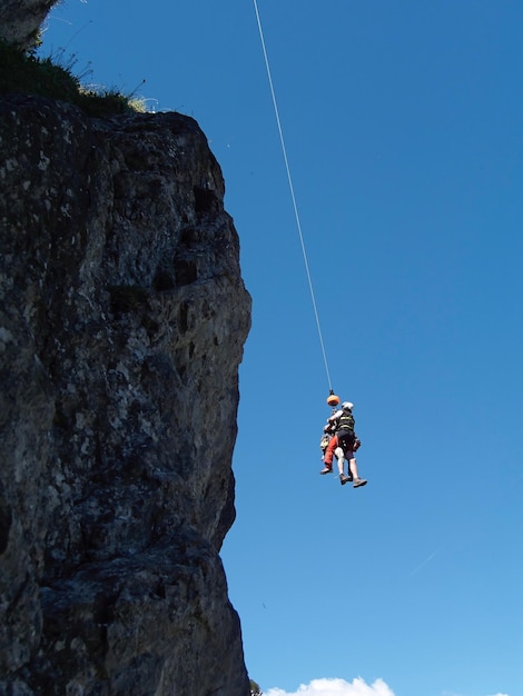 Foto vista a bassa angolazione di persone appese a una corda contro il cielo blu