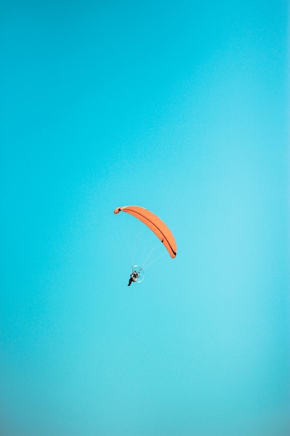 Low angle view of person paragliding against clear blue sky