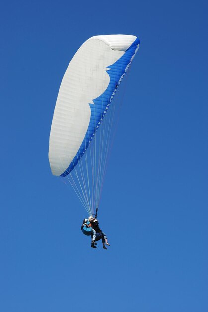 Low angle view of person paragliding against clear blue sky