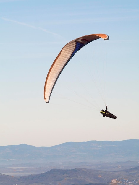 Foto vista a basso angolo di una persona in parapendio contro un cielo limpido