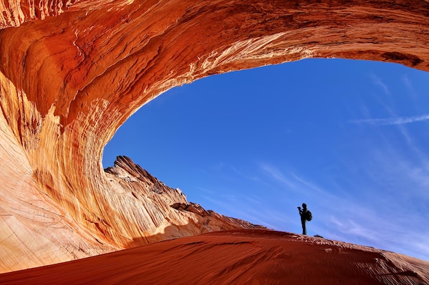 Low angle view of person standing at natural arch against blue sky