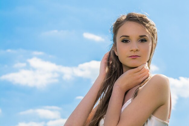 Photo low angle view portrait of beautiful young woman posing against sky outdoors