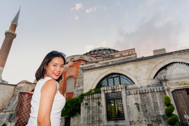 Foto ritratto a basso angolo di una donna sorridente che punta mentre si trova contro un edificio