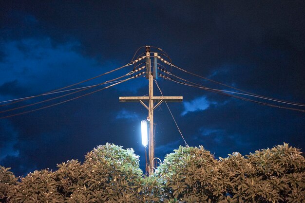 Foto vista a basso angolo della linea elettrica contro un cielo nuvoloso di notte