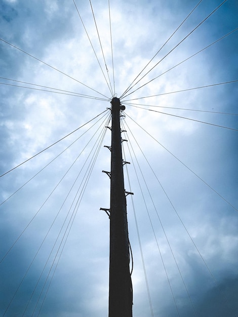 Foto vista a basso angolo della linea elettrica contro un cielo nuvoloso