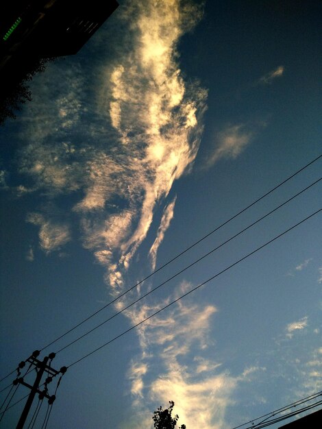 Low angle view of power lines against cloudy sky