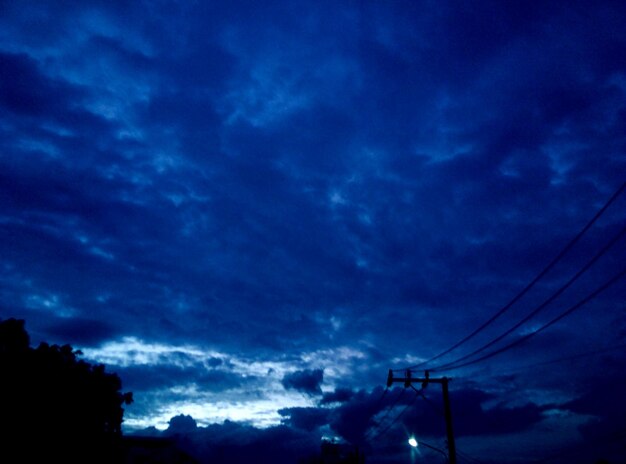 Low angle view of power lines against cloudy sky