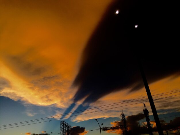 Low angle view of power lines against cloudy sky