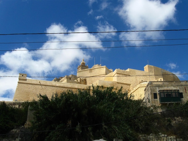 Low angle view of power lines and buildings against sky