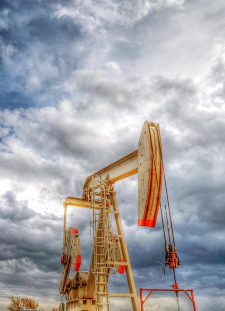 Photo low angle view of pump jack against cloudy sky