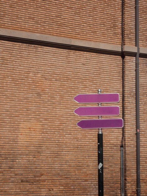 Photo low angle view of purple street signs on brick wall