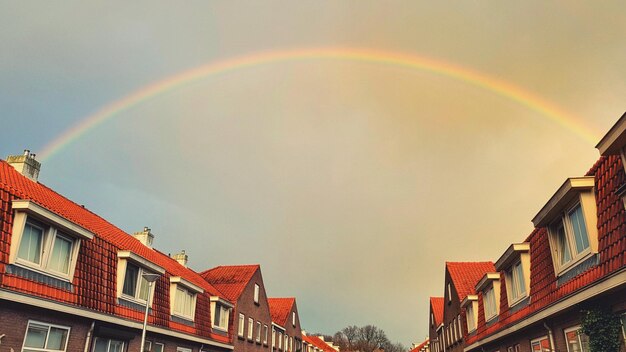 Low angle view of rainbow over buildings against sky