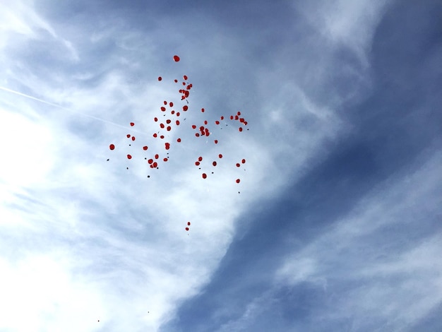 Foto vista a bassa angolazione di palloncini rossi che volano contro un cielo nuvoloso