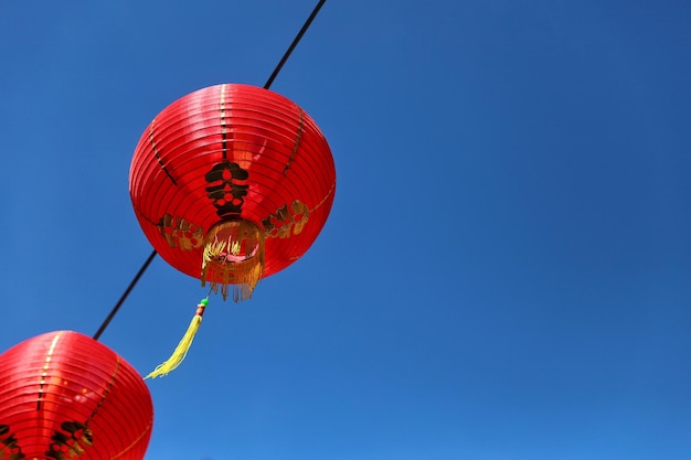 Low angle view of red lanterns hanging against clear blue sky