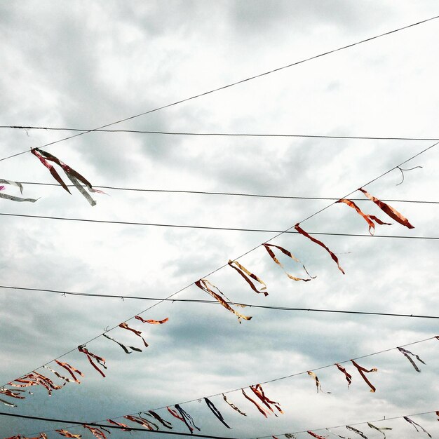 Photo low angle view of ribbons hanging on cables against sky