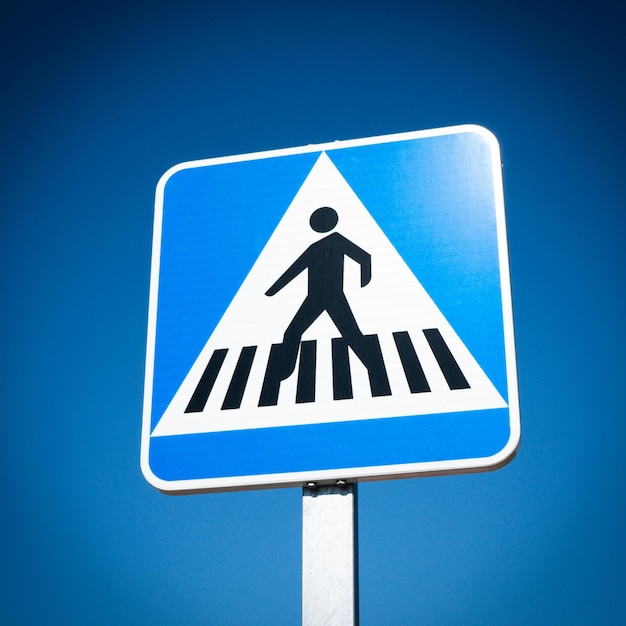 Low angle view of road sign against blue sky