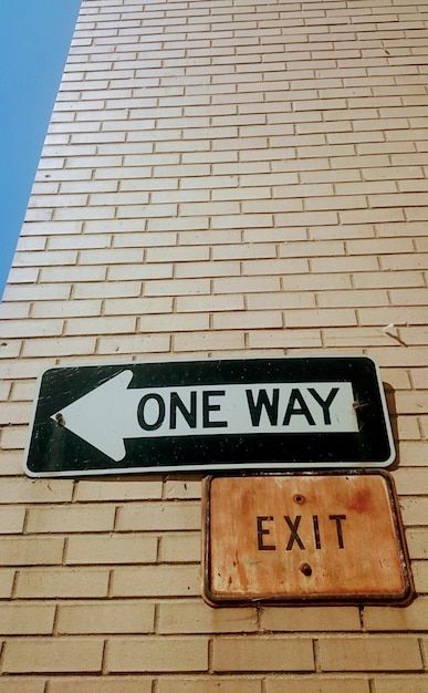 Low angle view of road sign against brick wall