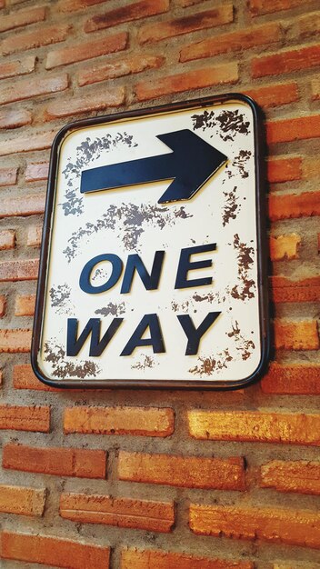 Photo low angle view of road sign on brick wall