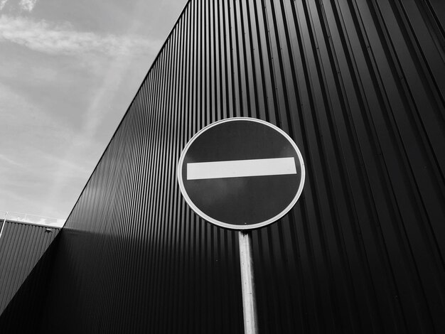 Photo low angle view of road sign by buildings against sky