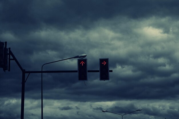 low angle view of road signal against cloudy sky
