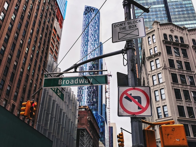 Photo low angle view of road signs against buildings in city