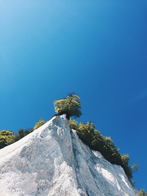 Low angle view of rocks against clear blue sky