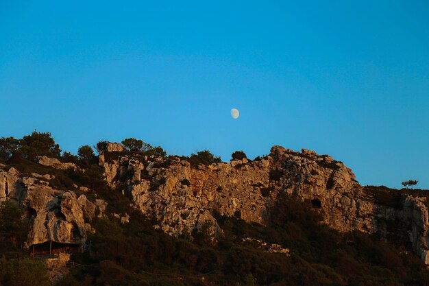 Low angle view of rocks against clear blue sky