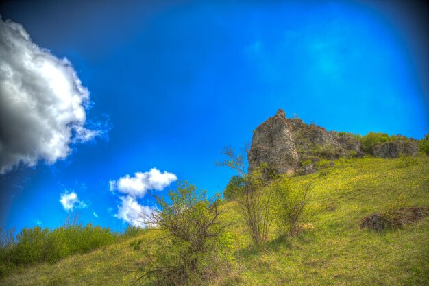 Low angle view of rocky mountain against blue sky