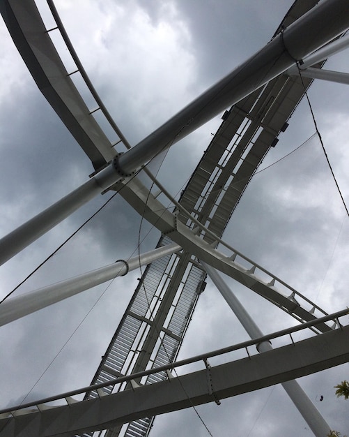 Low angle view of rollercoaster track at amusement park against cloudy sky
