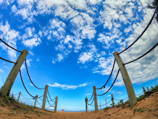 Low angle view of rope fence against sky