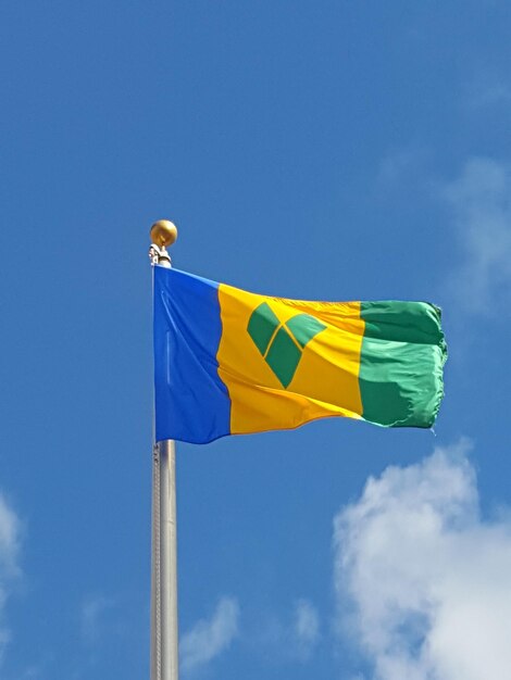 Низкоугольный вид флага Сент-Винсента и Гренадин на голубом небе