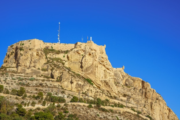 Низкий угол обзора замка Санта-Барбара в городе Аликанте, Испания, на фоне голубого неба