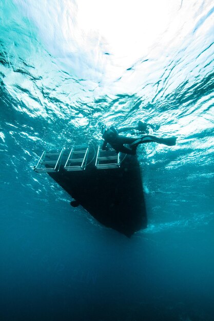 Low angle view of scuba driver by boat in sea at ishigaki