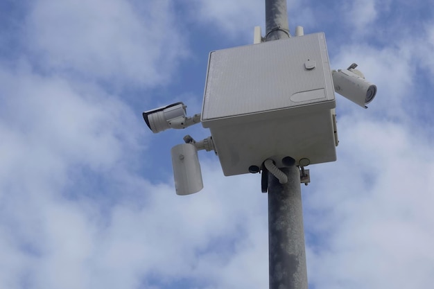 Low angle view of security cameras against cloudy sky