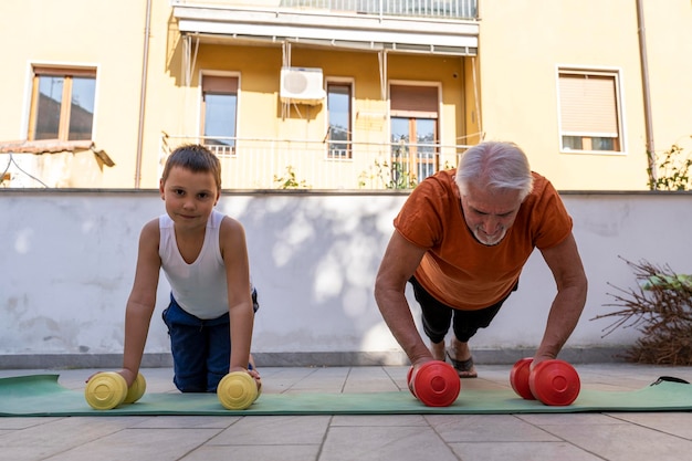 Foto vista ad angolo basso di un uomo anziano con il nipote che solleva manubri all'aperto