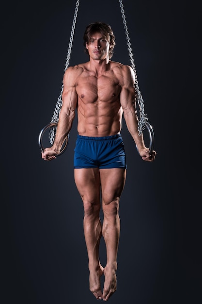 low angle view of shirtless boy swinging against clear sky