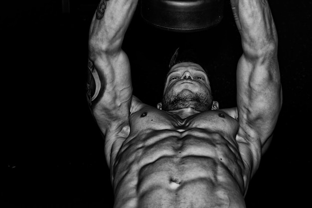 Low angle view of shirtless man exercising against black background