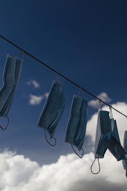 Photo low angle view shot of masks hanging on clothesline against sky