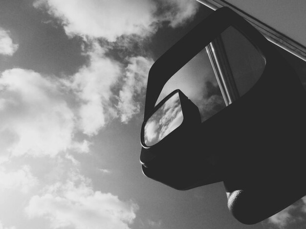 Low angle view of side-view mirror against sky