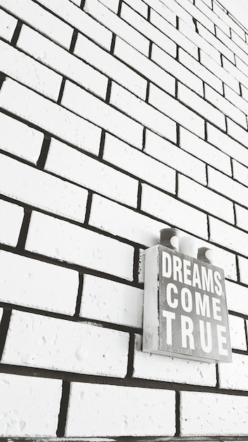 Photo low angle view of sign board on brick wall